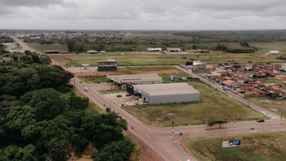 Aerial shot of suburban landscape featuring roads, warehouses, and greenery under a cloudy sky.