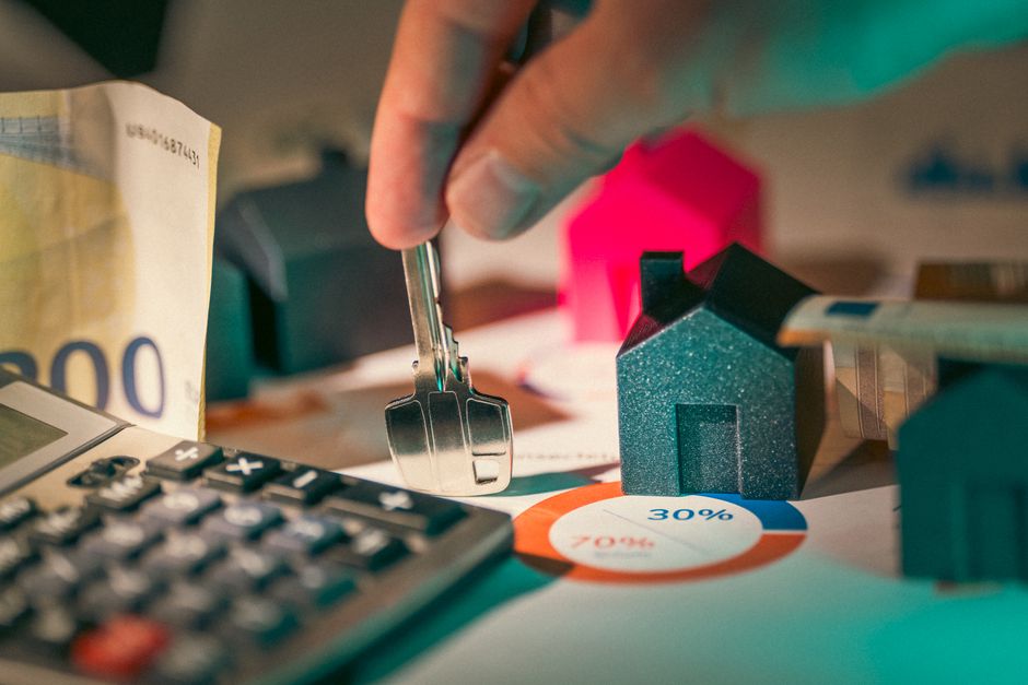 A close-up of real estate financial planning with keys, calculator, and money.