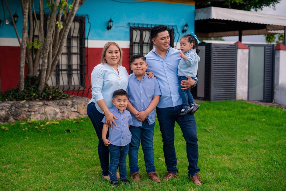 Candid family portrait outdoors with vibrant house background.